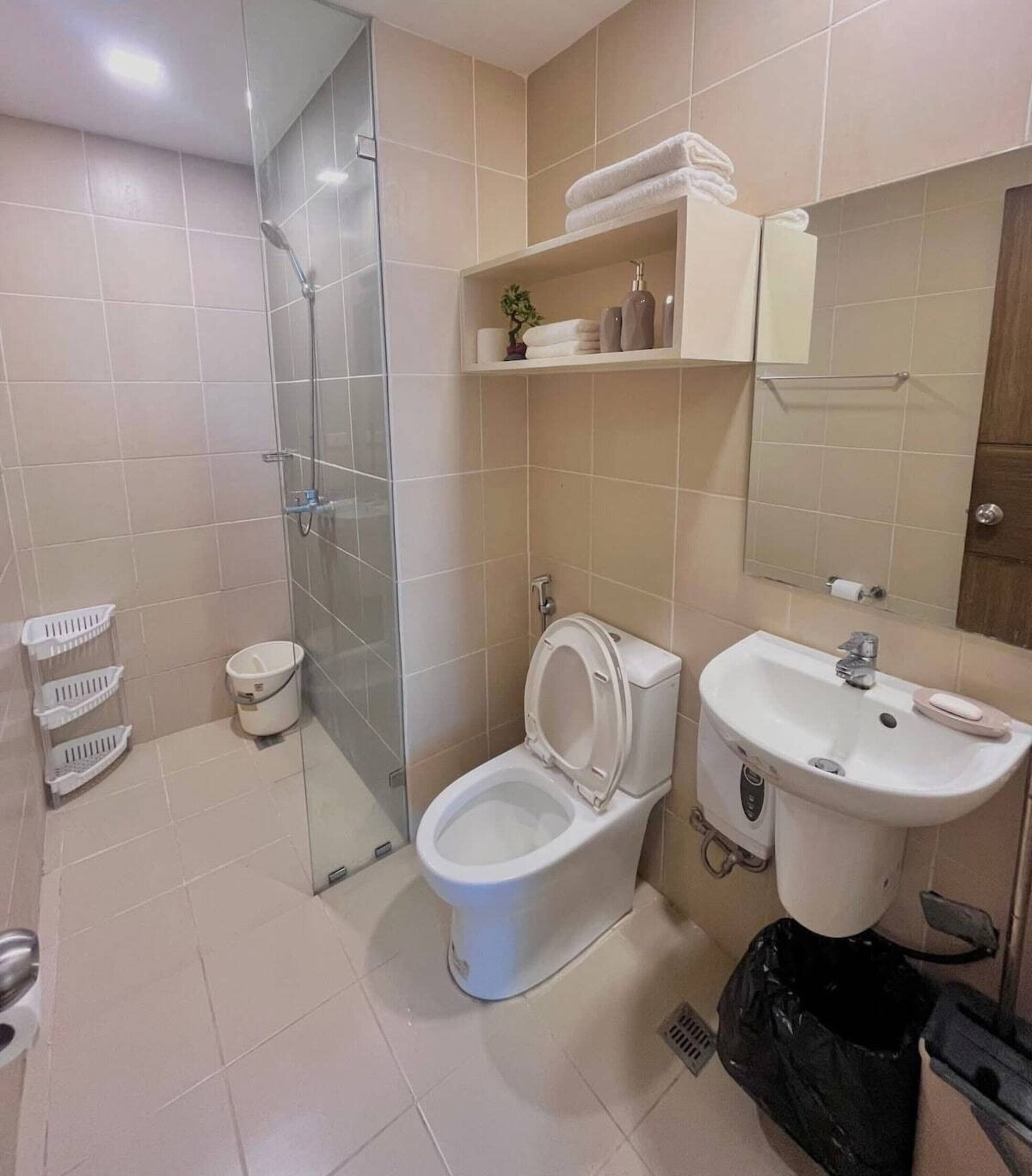 Un baño con ducha de vidrio, inodoro, lavamanos y espejo.