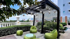 A rooftop terrace with a pergola, outdoor seating, and a view of the cityscape. - Cozy Studio at Lafayette Park (Iloilo)