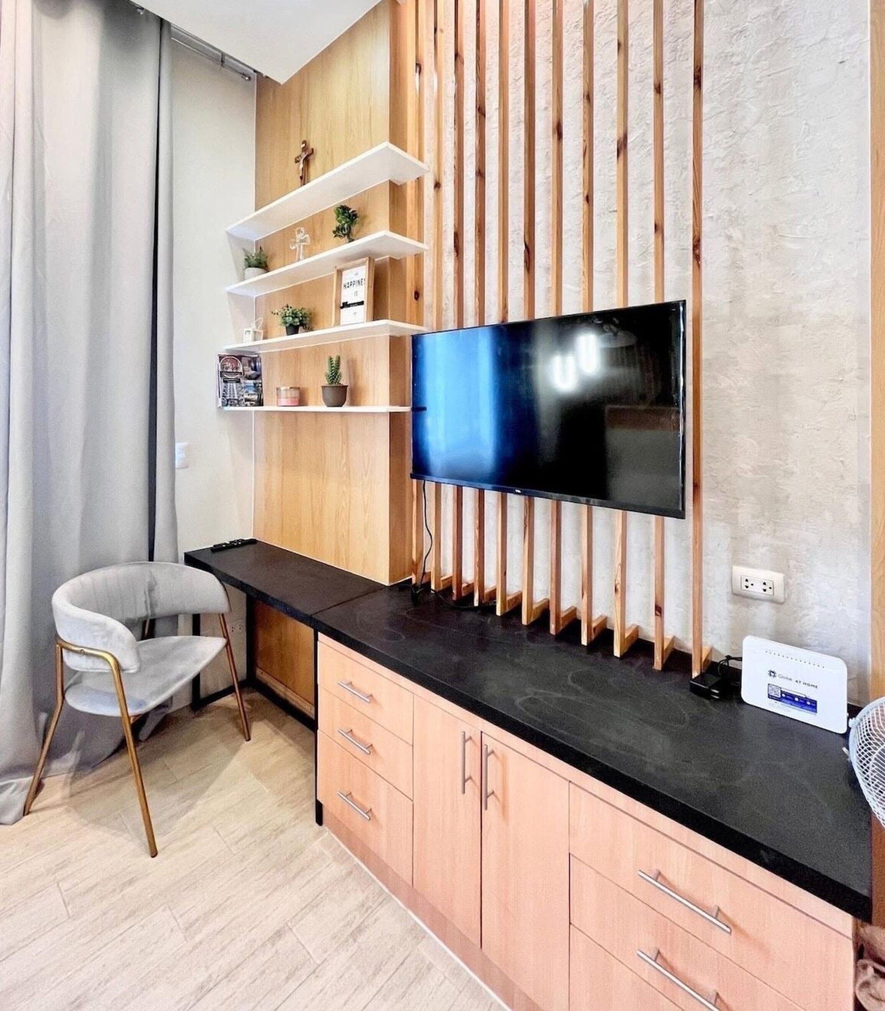 Eine moderne Küche mit Flachbildfernseher an einer Holzwand, einer schwarzen Arbeitsplatte und einem Stuhl.