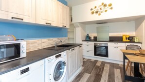 A compact kitchen with a washing machine, microwave, sink, and coffee maker.