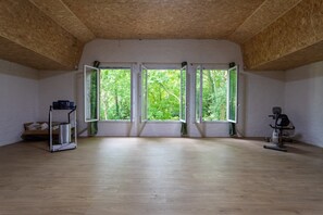 Ein Zimmer mit Holzboden, großen Fenstern und Fitnessgeräten.