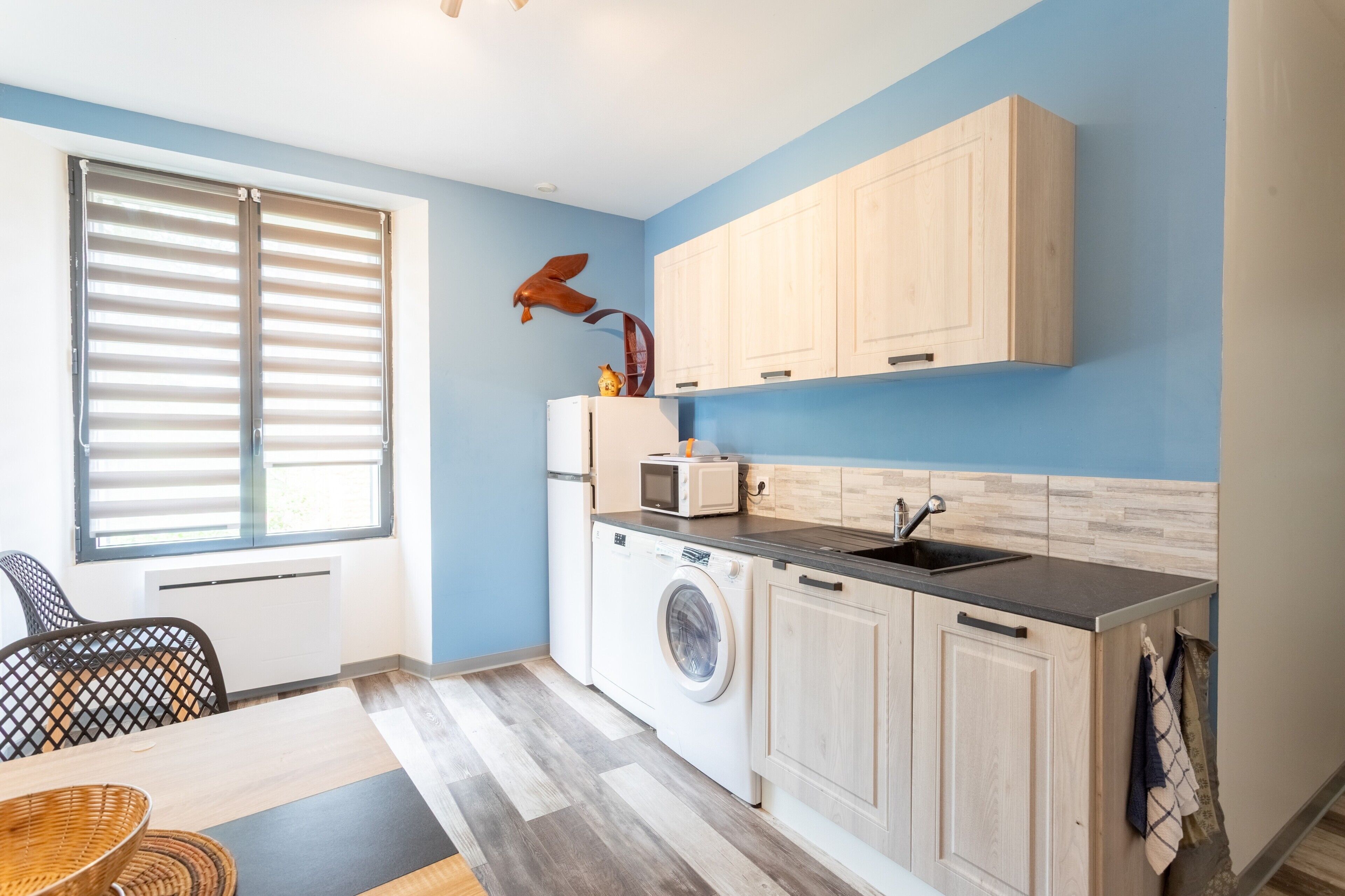 A compact kitchen with a washing machine, a microwave, and wooden cabinets.