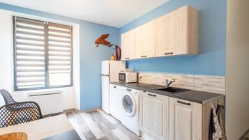 A compact kitchen with a washing machine, a microwave, and wooden cabinets.