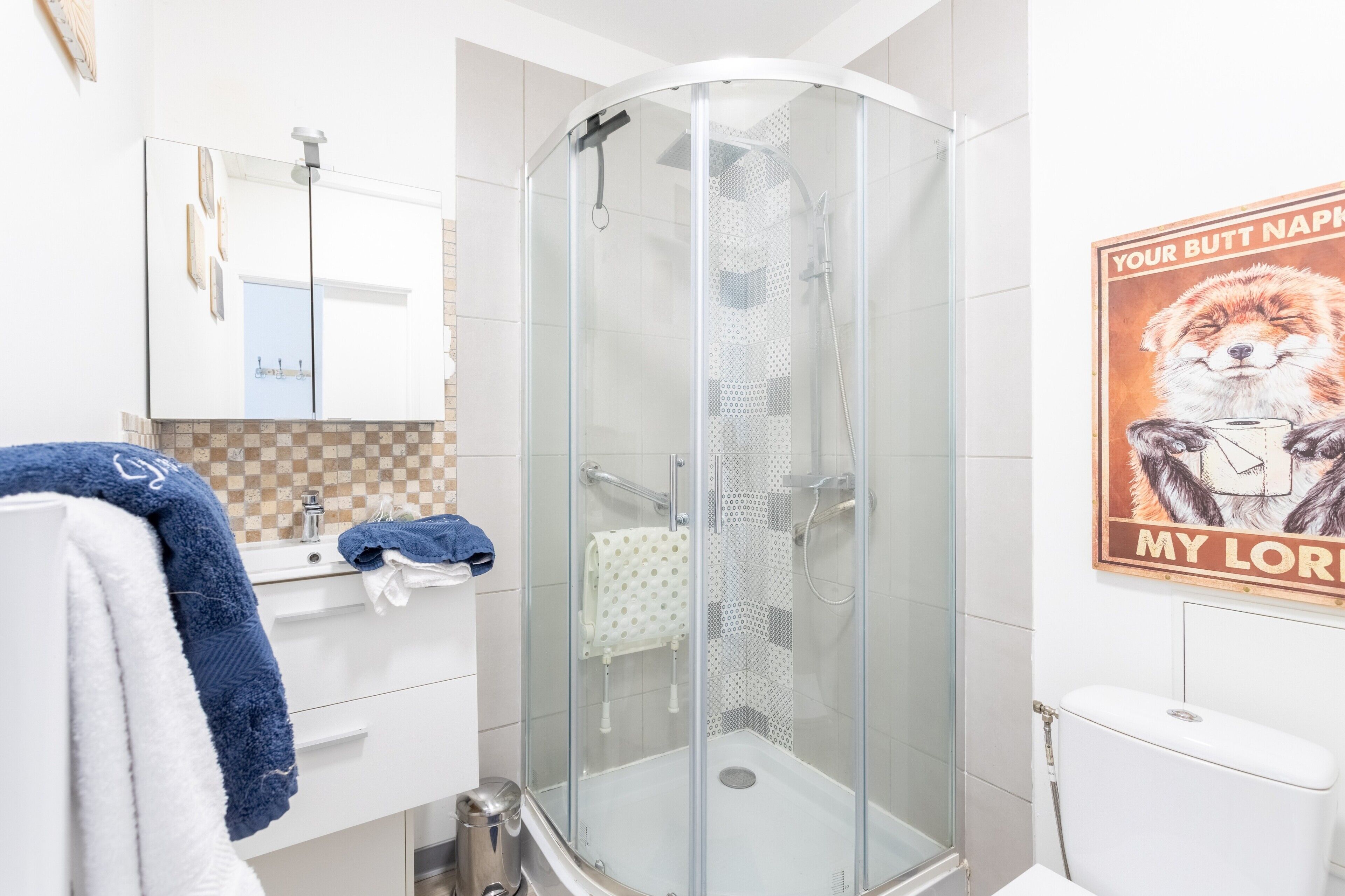 A modern bathroom with a glass-enclosed shower, a white sink with a mirror, and a toilet.