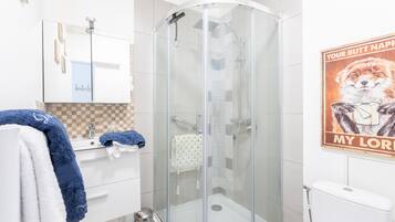 A modern bathroom with a glass-enclosed shower, a white sink with a mirror, and a toilet.