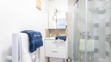 A bathroom with a glass shower enclosure, a white sink, and a mirror above it.
