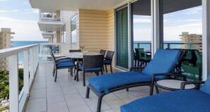 Ein Balkon mit Gartenmöbeln, einem Tisch und Blick aufs Meer.