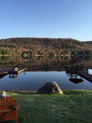 A tranquil lakeside setting with a dock, a gazebo, and a wooden chair.