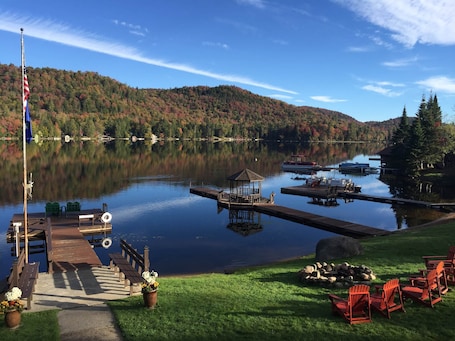 A lakeside dock with a gazebo, boats, and a flagpole.. Evergreen - Big Moose Lakeside