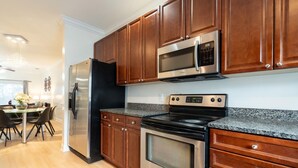A modern kitchen with stainless steel appliances, wooden cabinets, and a granite countertop. - Modern Charleston Getaway (North Charleston)