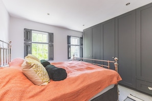 A bedroom with a bed, two windows with shutters, a wardrobe, and a radiator. - Spacious 2BDR Home w WiFi Garden Sleeps 4 (Twickenham)