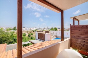 Terraza en la azotea con piscina, pérgola de madera y vistas a la ciudad.