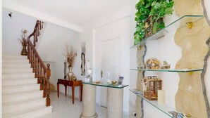 A staircase with wooden balusters, a white door, a glass shelf with decorative items, and a textured wall. - Room 'South Side Guesthouse - Quarto E' with Shared Pool, Wi-Fi and Air Conditioning (Quelfes)