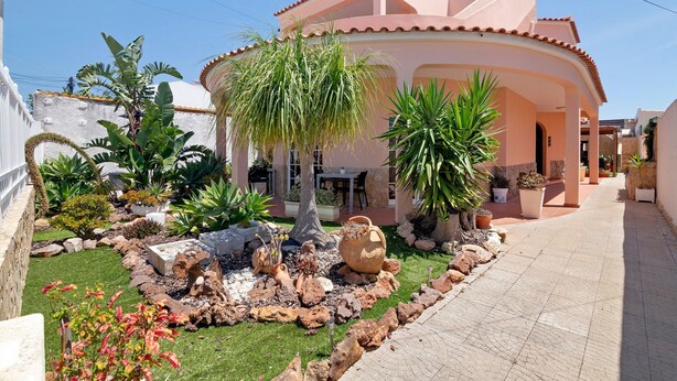 A house with a garden, a tiled patio, and a clear sky. - Room 'South Side Guesthouse - Quarto E' with Shared Pool, Wi-Fi and Air Conditioning (Quelfes)