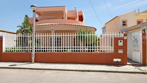 A two-story house with a white fence, a brick wall, and a tiled roof. - Room 'South Side Guesthouse - Quarto E' with Shared Pool, Wi-Fi and Air Conditioning (Quelfes)