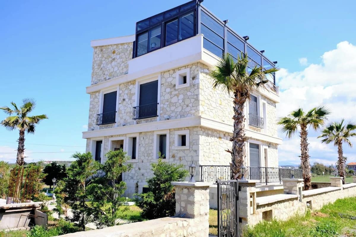 A multi-story building with stone facade, balconies, and a gated entrance.