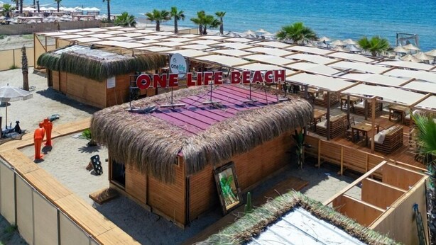 A beachside resort with thatched-roof structures, sun loungers, and a clear view of the sea. - one lıfe stone (Ayvalık)