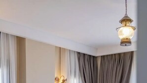 A neatly made bed with a grey headboard, a bedside table, and a hanging light fixture. - one lıfe stone (Ayvalık)