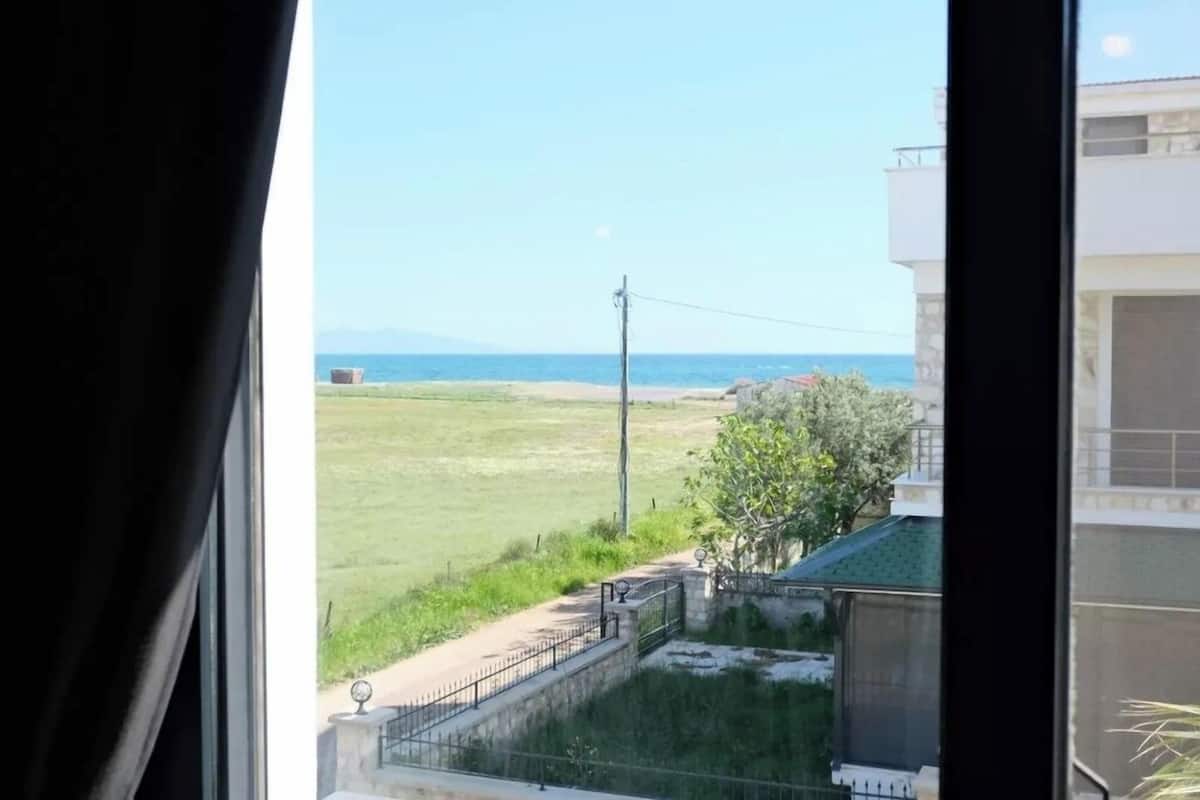 A view from a window overlooking a grassy field with a building and a power line in the distance.