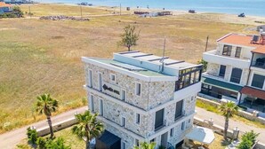 A multi-story hotel with a stone facade, balconies, and a pool area. - one lıfe stone (Ayvalık)