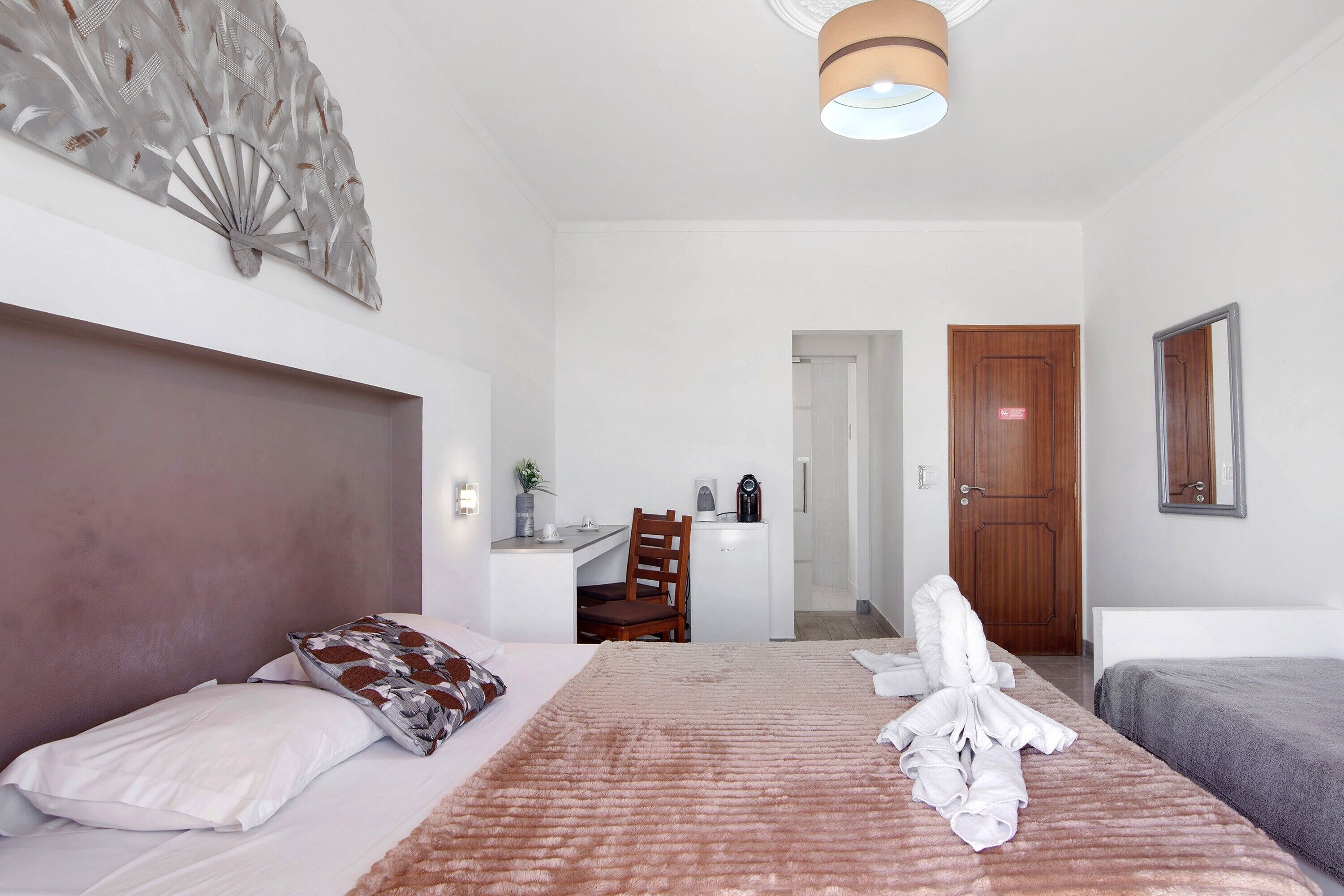 Een hotelkamer met een bed, een bureau, een stoel en een deur.