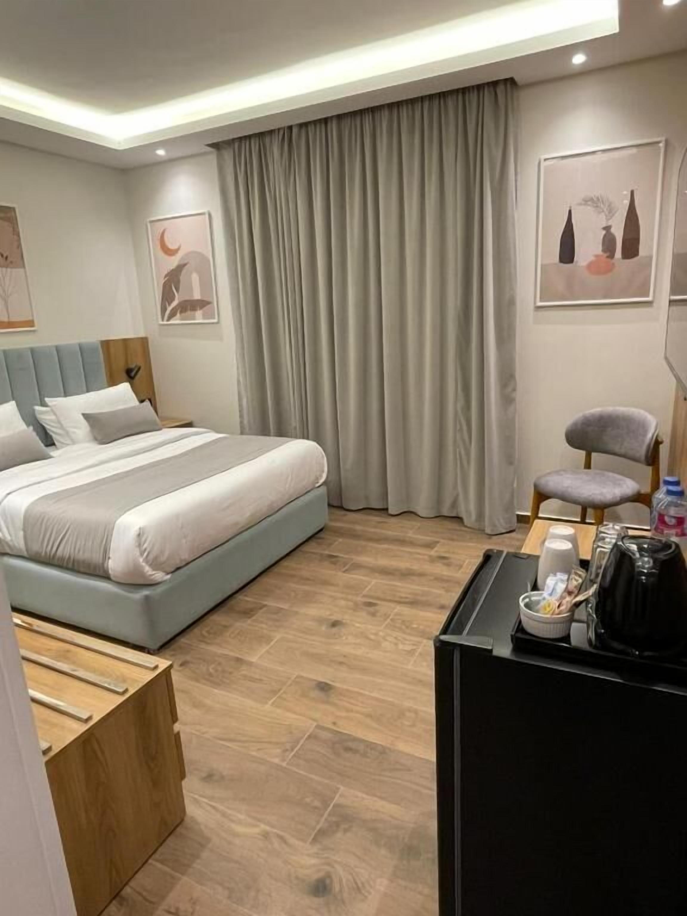 Una habitación de hotel moderna con una cama, un escritorio, una silla y obras de arte en las paredes.