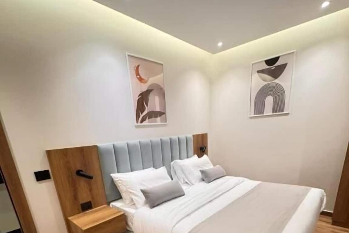 A modern bedroom with a bed, nightstands, and artwork on the walls.