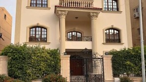 Un edificio de dos pisos con fachada simétrica, ventanas amplias y un balcón central.