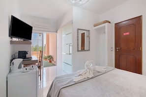 Une chambre dâhĂŽtel Ă©quipĂ©e dâun lit, dâune tĂ©lĂ©vision, dâun bureau avec une machine Ă cafĂ© et offrant une vue sur lâextĂ©rieur.