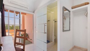 A room with a sliding glass door leading to a balcony, a shower area, and a mirror on the wall. - Room 'South Side Guesthouse - Quarto W' with Shared Pool, Wi-Fi and Air Conditioning (Quelfes)