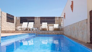 A swimming pool with tiled edges, lounge chairs, and a stone wall with decorative elements. - Room 'South Side Guesthouse - Quarto W' with Shared Pool, Wi-Fi and Air Conditioning (Quelfes)