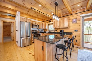 Ein Holzblockhaus-Interieur mit Küche, Barhocker und einer großen Kochinsel.