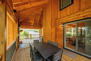 Une cabane en bois dotée d’un coin repas, d’une véranda et offrant une vue sur le paysage environnant.