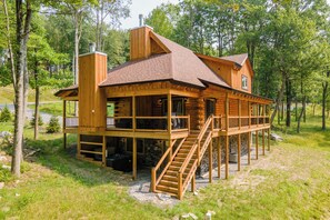 Eine Holzhütte mit einer überdachten Terrasse und einer Treppe, die zu einer zweiten Ebene führt.