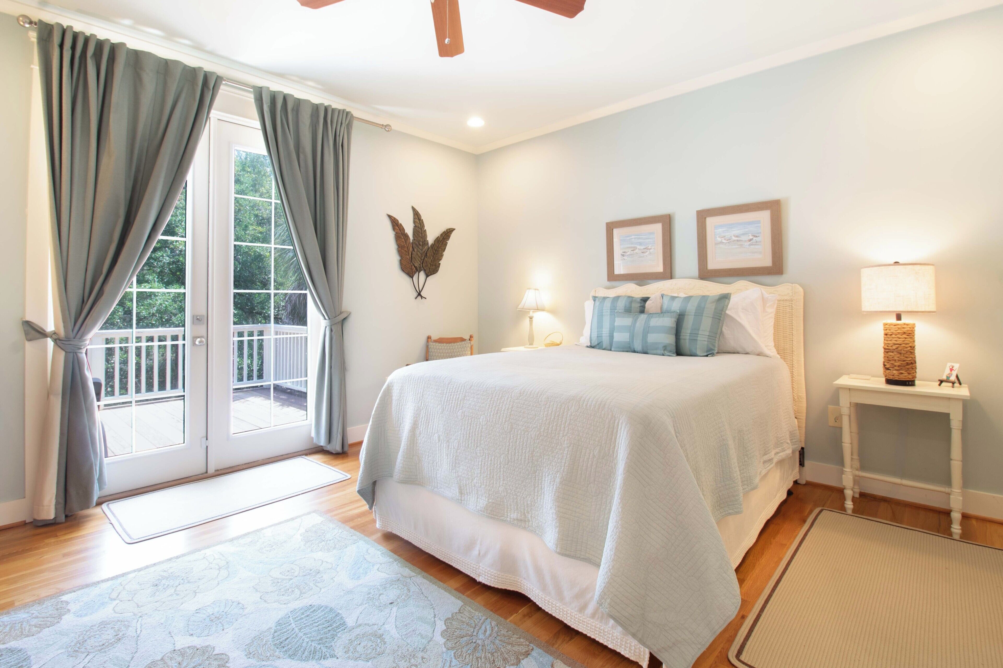 A bedroom with a bed, a nightstand, a lamp, a window with curtains, and a wall-mounted decoration.