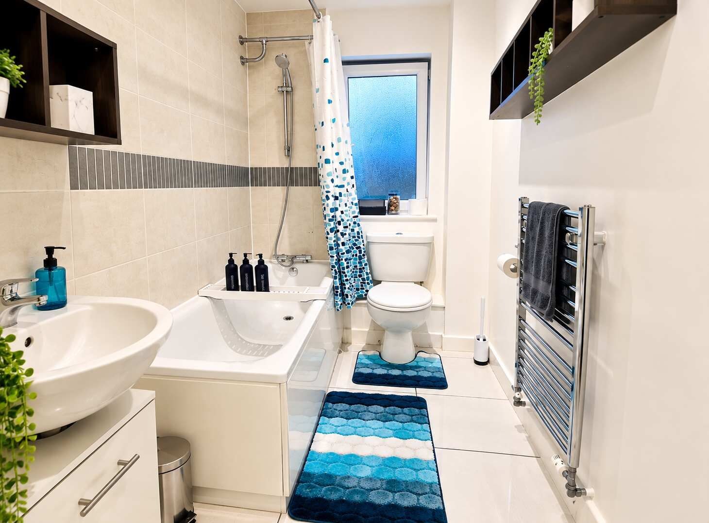 Un baño moderno con una bañera, dos lavamanos, un inodoro y un perchero para toallas.