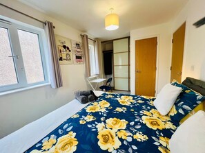 A bedroom with a bed, a chair, a wardrobe, and a window. - 3BR Contractor House Parking 2 Bath (Luton)