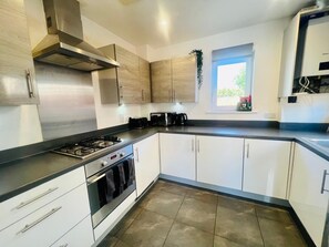 A modern kitchen with stainless steel appliances, white cabinetry, and a window providing natural light. - 3BR Contractor House Parking 2 Bath (Luton)