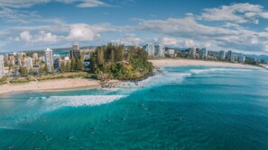 A coastal cityscape with high-rise buildings, a sandy beach, and clear turquoise waters. - Coral Gardens Unit 5 (Tweed Heads)