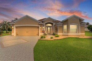Ein zweigeschossiges Haus mit Garage, überdachter Eingangspforte und gepflegtem Rasen.