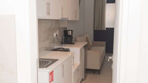 Una piccola cucina compatta completa di macchina per caffè, forno a microonde e lavandino.