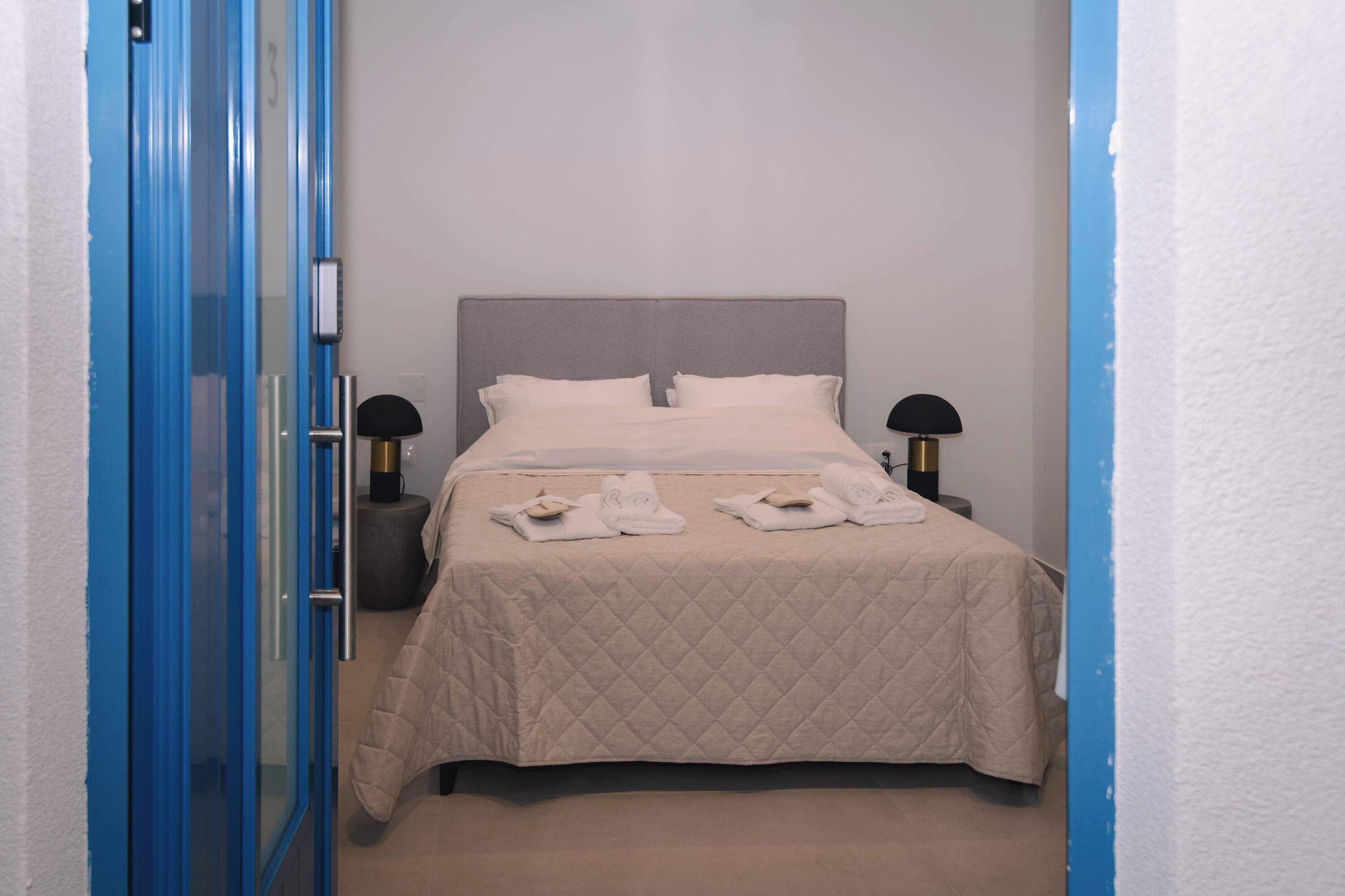 A hotel room with a bed, two bedside tables, a door, and a wall.