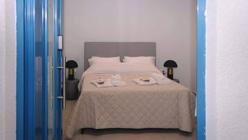 A hotel room with a bed, two bedside tables, a door, and a wall.
