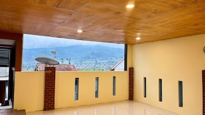 A room with a wooden ceiling, a view of a town through a window, and a satellite dish. - Villa Garcinia 111 Ciwidey (Pasirjambu)