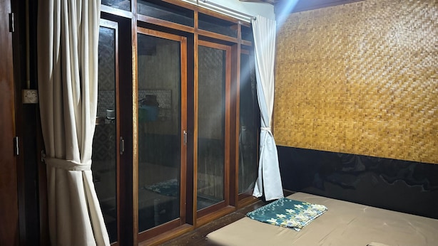 A room with a sliding glass door, a woven wall, and a mat on the floor. - Villa Garcinia 111 Ciwidey (Pasirjambu)