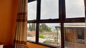 A room with a large window, curtains, and a view of a residential area. - Villa Garcinia 111 Ciwidey (Pasirjambu)