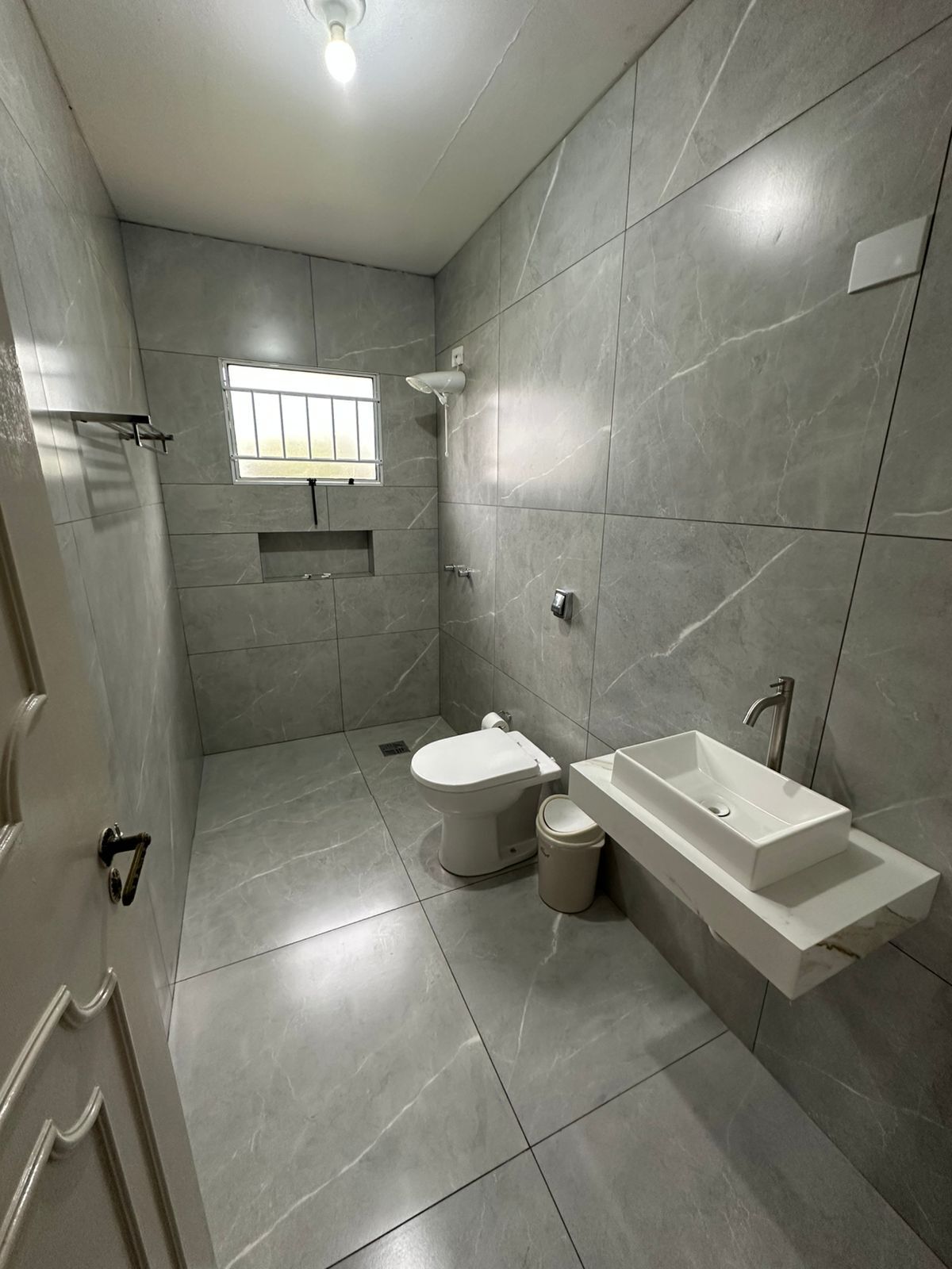 Un baño moderno con inodoro, bidé y lavamanos, todo con un diseño elegante y minimalista.