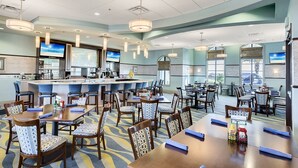 A hotel dining area with multiple tables and chairs, a bar, and large windows. - Dream Vacation Villa Near Theme Parks with Pool! (Davenport)
