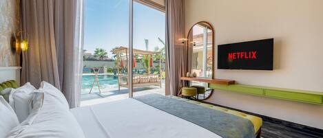 A hotel room with a bed, a TV, a view of an outdoor pool, and a balcony.