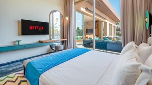 A hotel room with a bed, a TV mounted on the wall, a large window, and a view of the outdoor area. - Villa Cyrine (Marrakech)